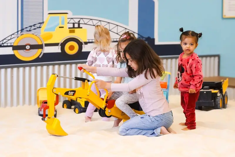 four little girls playing in the sandbox together