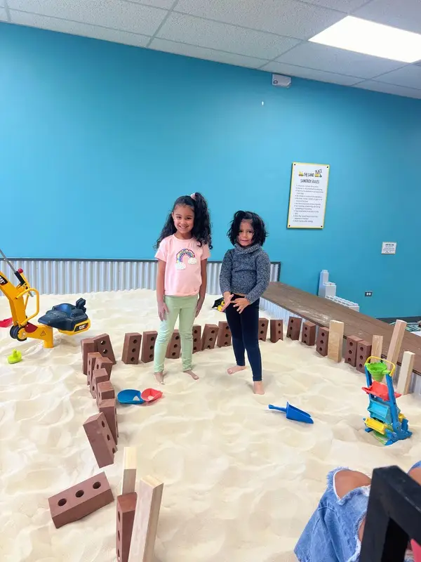 two girls building a fort in our indoor sandbox