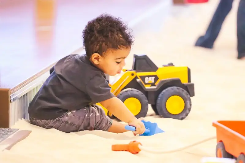 Kids laughing while digging and exploring the giant indoor sandbox play area.
