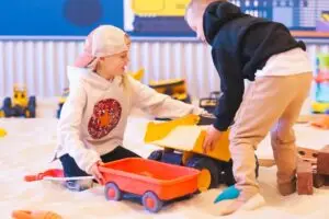 Two older children digging with construction toys at The Sand Place, an affordable indoor playground in Aurora offering sensory play for all ages.