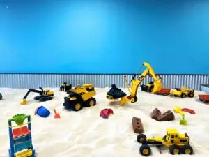 A bright, construction-themed indoor sandbox at The Sand Place in Aurora, Colorado—filled with toy trucks, diggers, and colorful play tools. Perfect for toddlers and young kids, this hands-on play zone encourages creativity, sensory exploration, and nonstop fun at Aurora’s favorite indoor playground.