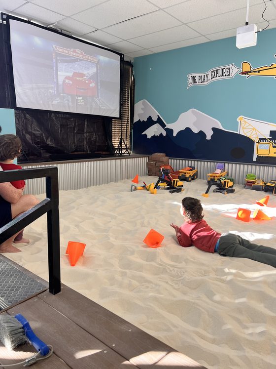 Kids relaxing in the sandbox watching a movie on the big screen at The Sand Place in Aurora