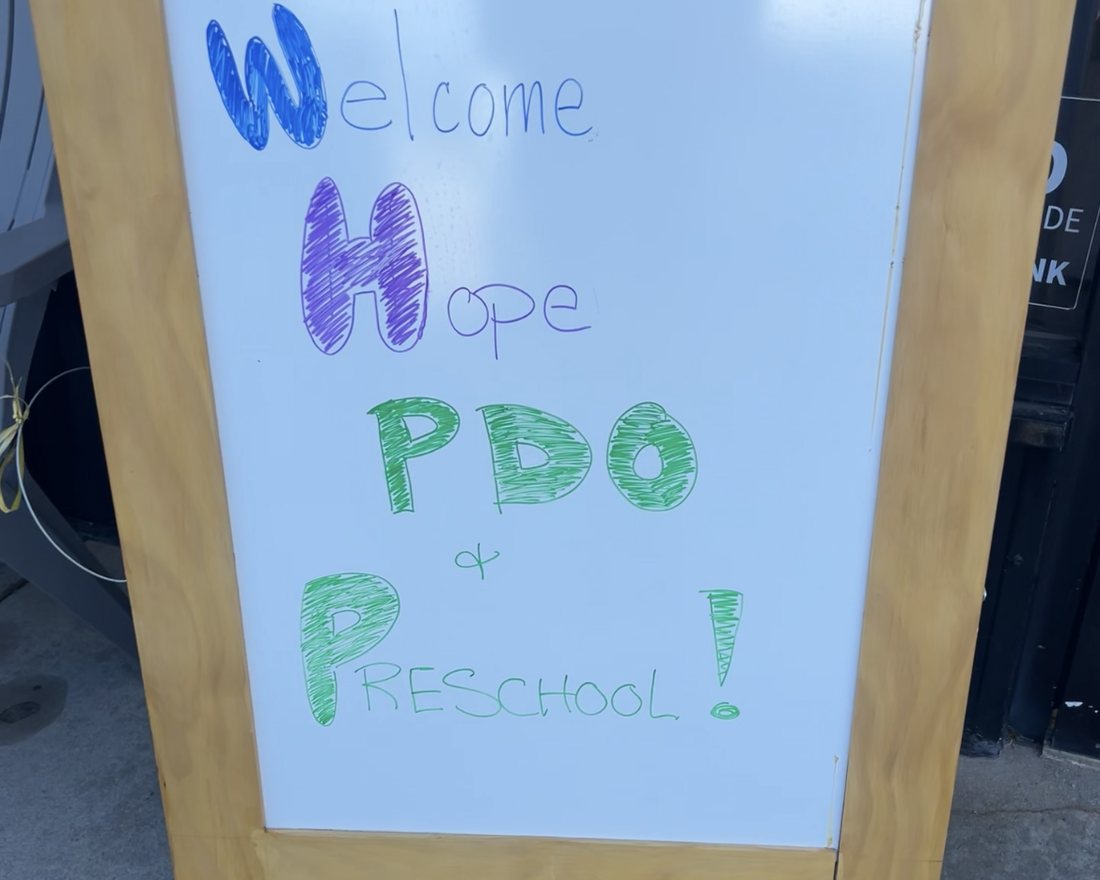 A hand-lettered sidewalk sign outside The Sand Place reading Welcome Hope PDO and Preschool